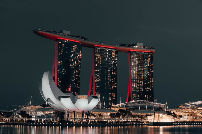 Marina Bay Sands lit red at night with the lotus-shaped ArtScience Museum in front