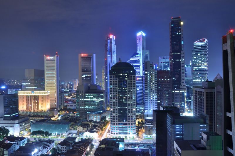 Singapore's financial district lit up at night above the roofs of old shophouses