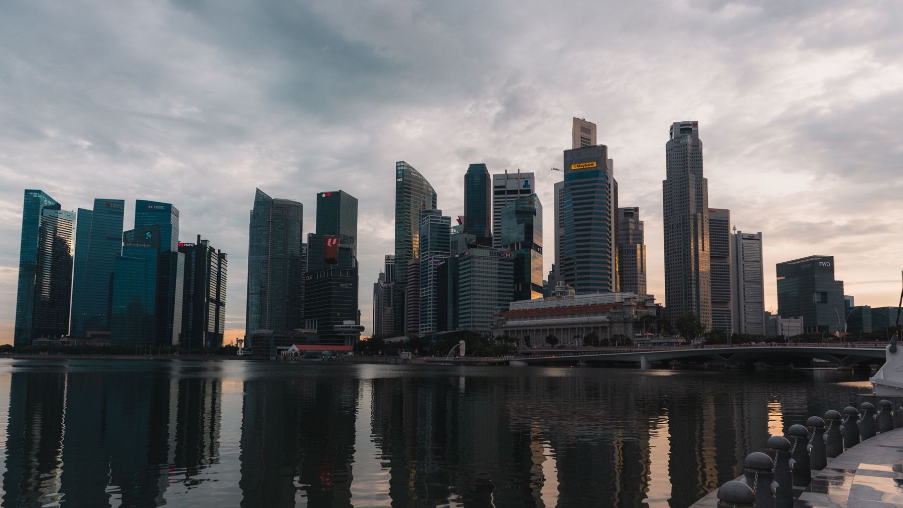 Clouds over the Singapore skyline and the Fullerton Hotel at sunset, reflected in Marina Bay