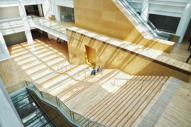 A spacious atrium with a wooden staircase in modern architectural design, located in Singapore.