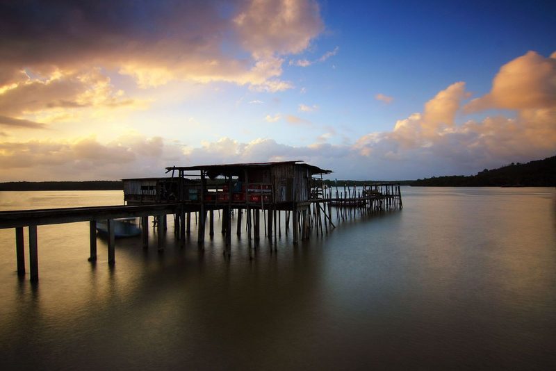 A tranquil sunset view with a rustic jetty on a calm lake, evoking peace and solitude.