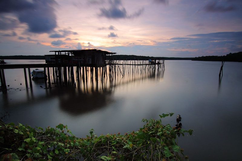 A tranquil scene of a jetty over calm waters at dusk, capturing reflections and serenity.