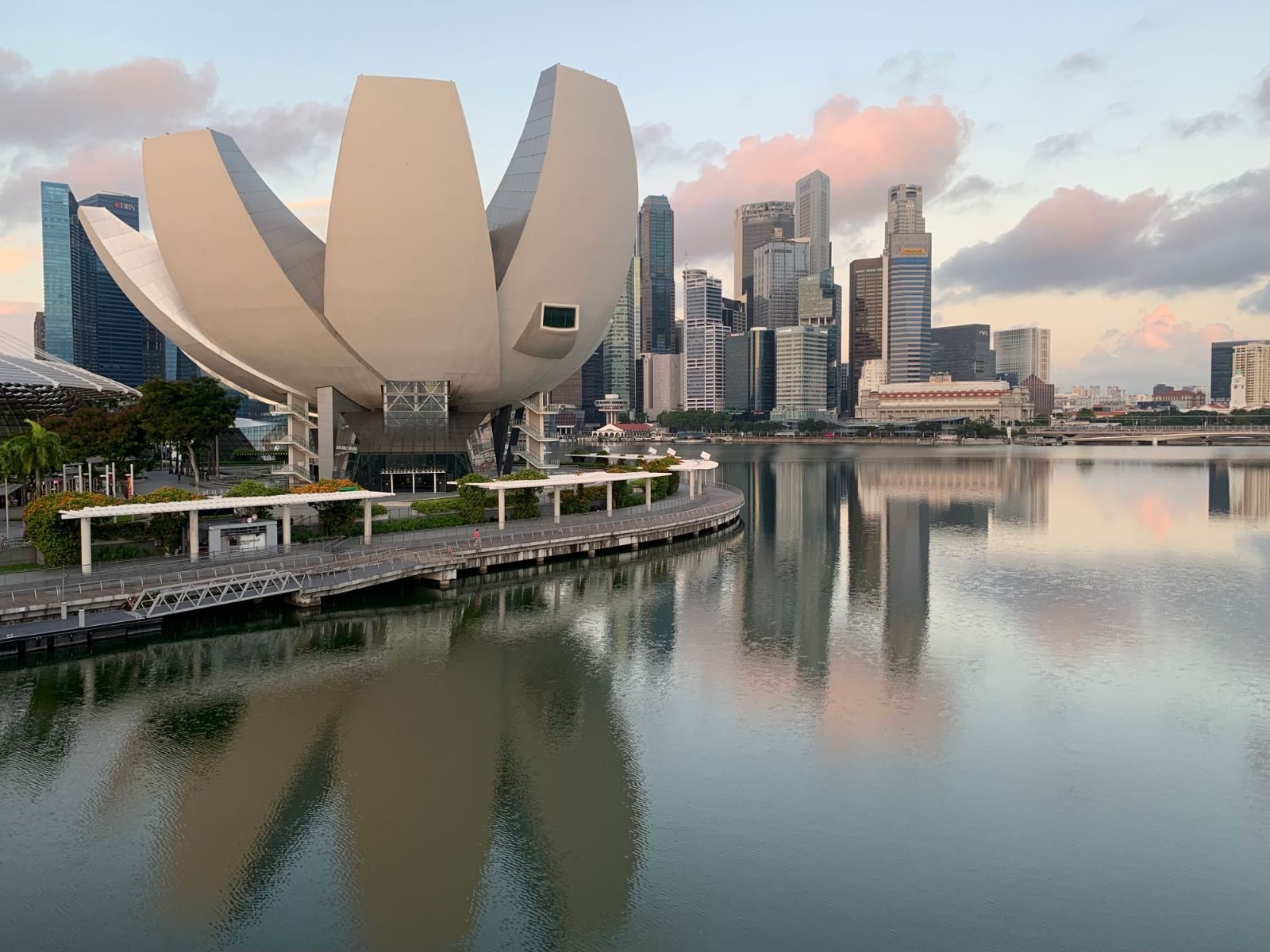 ArtScience Museum reflecting in Marina Bay with Singapore skyline at sunrise.