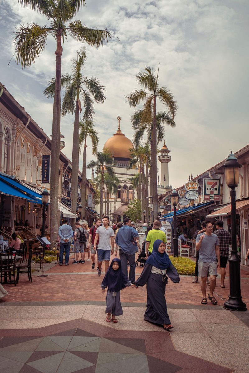 Lively street scene with tourists near the iconic Sultan Mosque in Singapore.