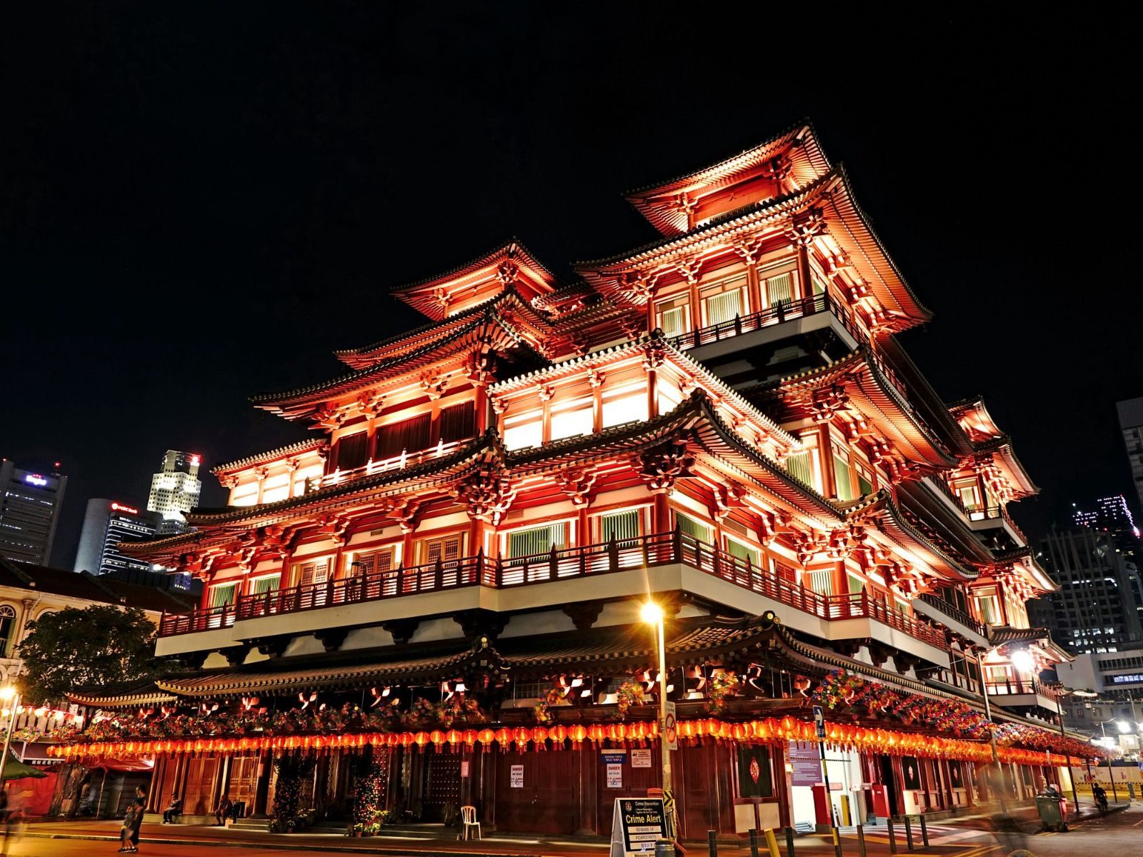Night view of the beautifully illuminated Buddha Tooth Relic Temple in Singapore, showcasing intricate architecture.
