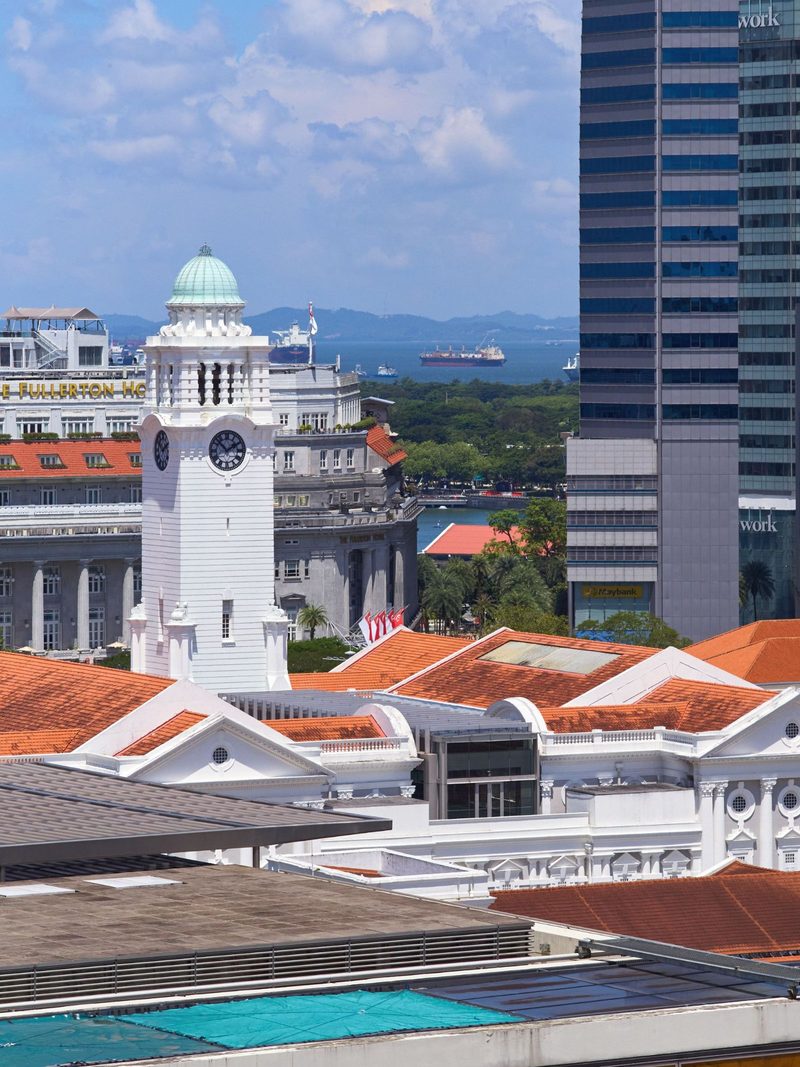 A scenic view of Victoria Theatre and Concert Hall with city skyscrapers in Singapore.