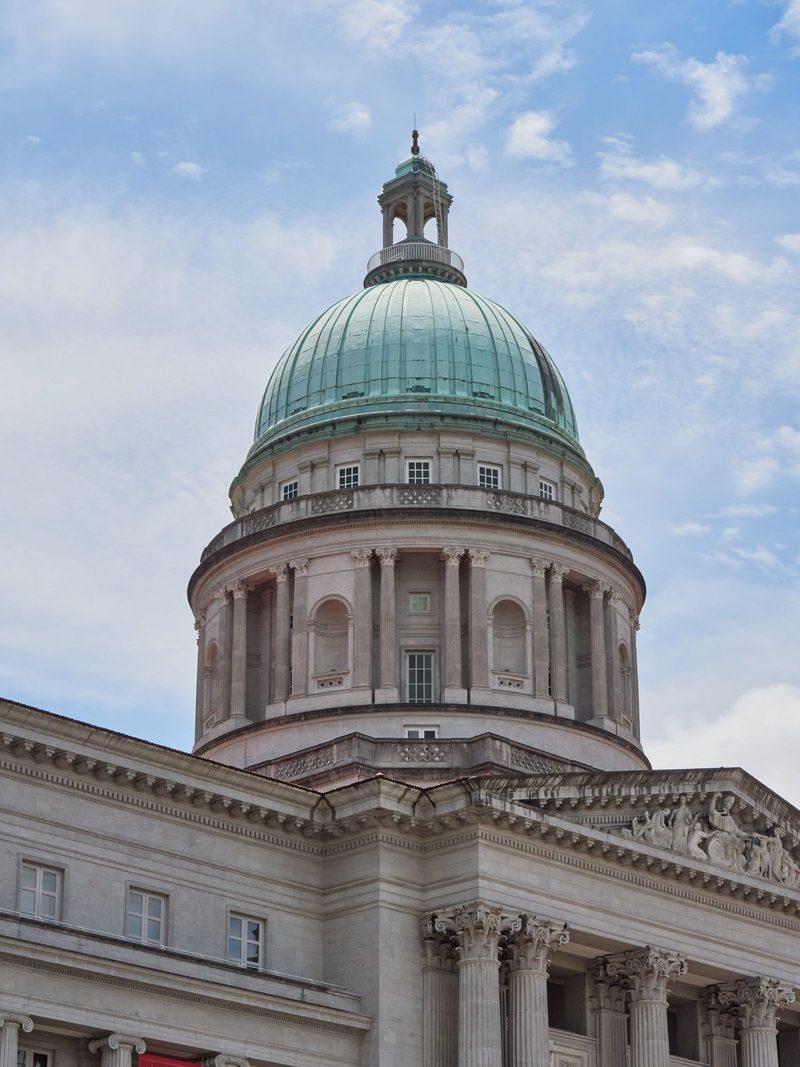 Elegant architectural dome of a historic building under a bright blue sky, showcasing classical design elements.