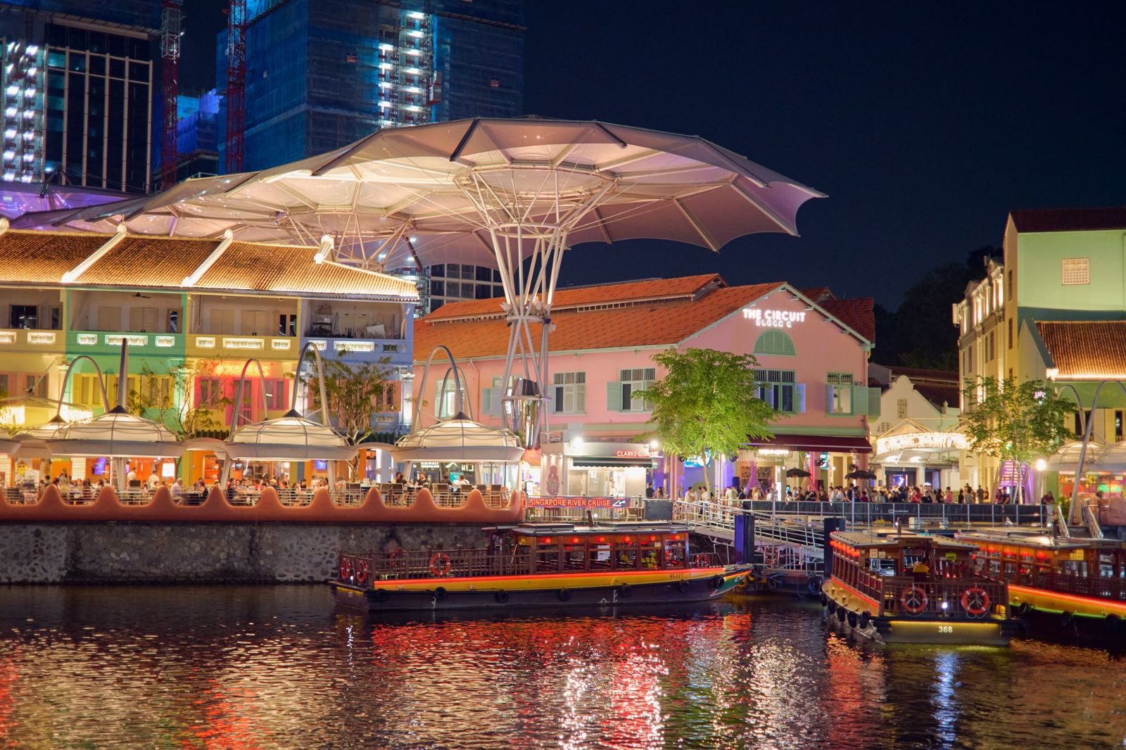 Colorful waterfront nightlife at Clarke Quay, Singapore, featuring illuminated architecture and boats.