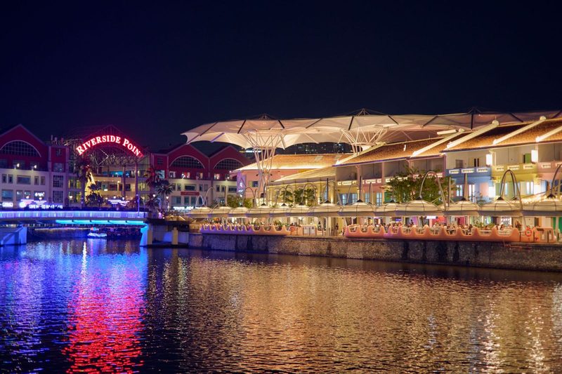 Night view of Riverside Point with colorful reflections over water.