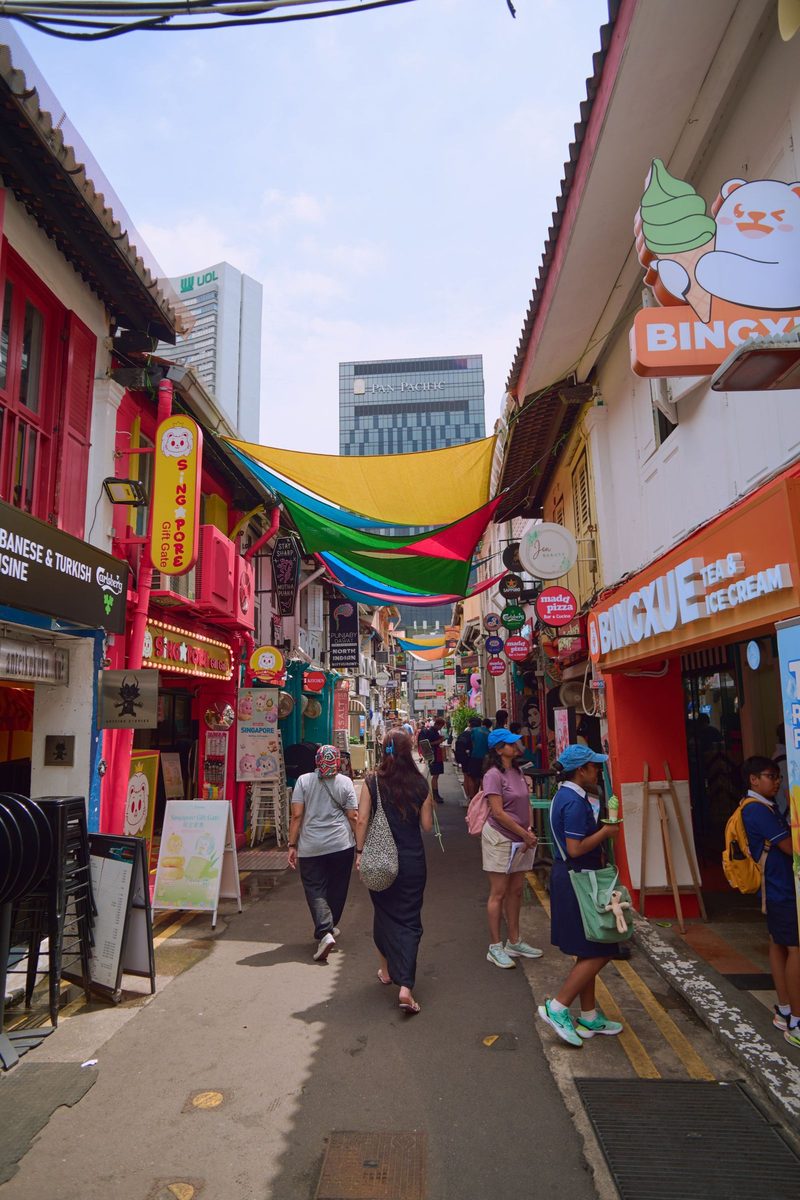 Vibrant day at a bustling street market lined with shops and colorful banners in Singapore.