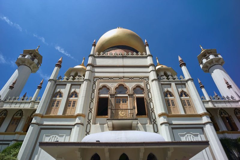 Stunning view of the Sultan Mosque with golden dome against a vibrant blue sky, showcasing Islamic architecture.