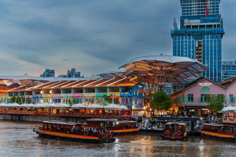 Scenic view of Clarke Quay with vibrant lights and riverboats in Singapore.