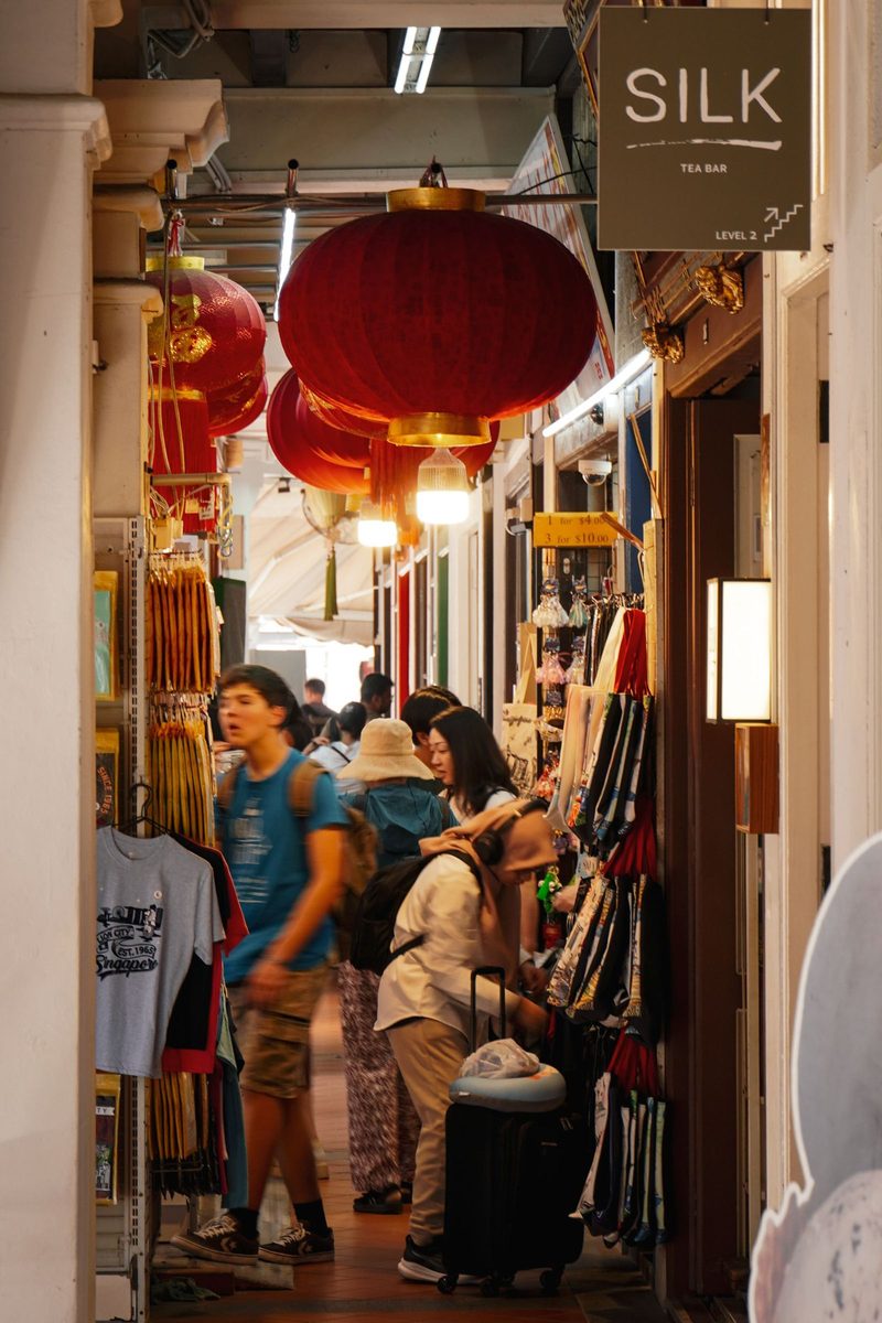 Vibrant Singapore market corridor with hanging red lanterns and busy shoppers.