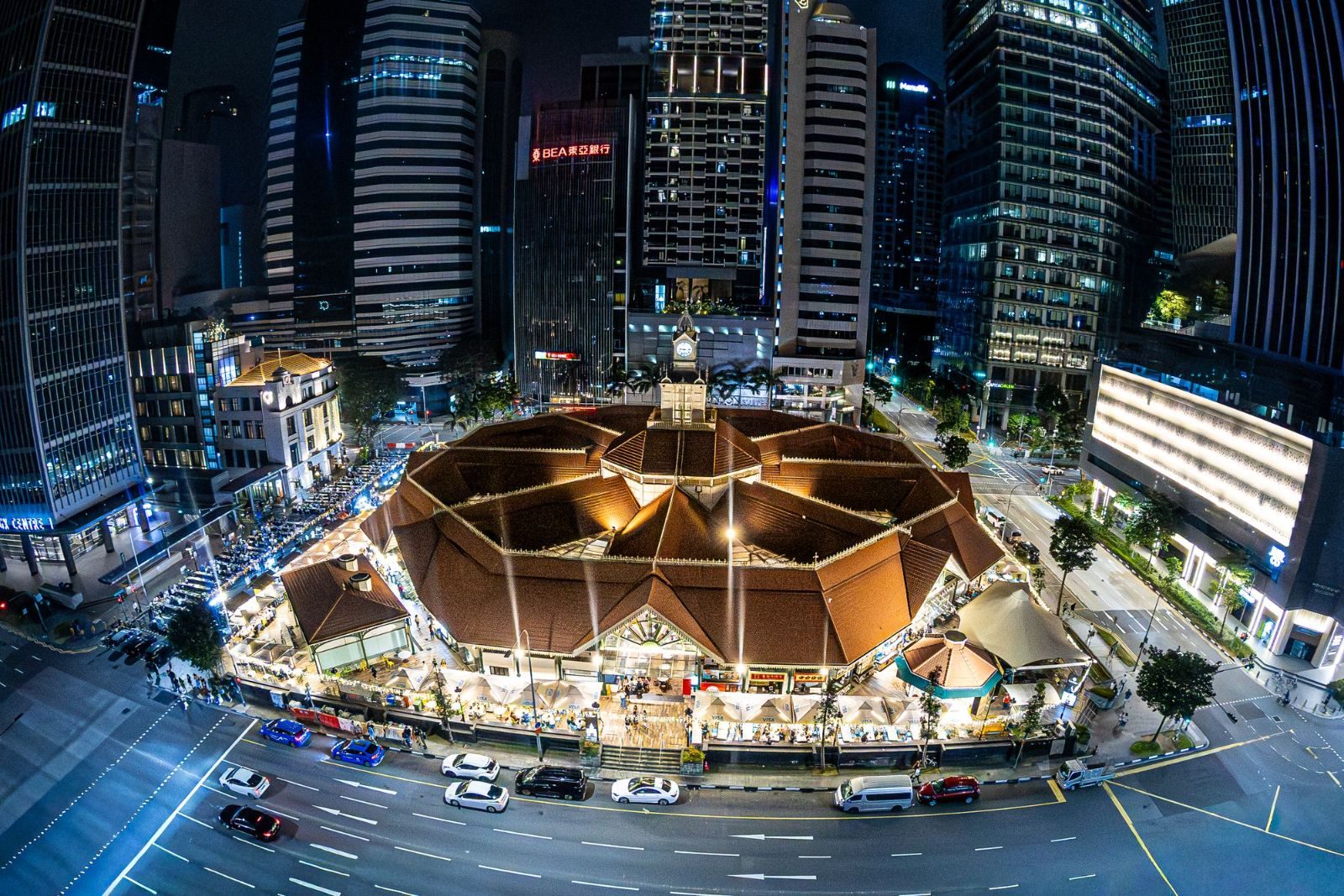 Captivating aerial night view of Lau Pa Sat, a famous food market in Singapore, surrounded by skyscrapers.