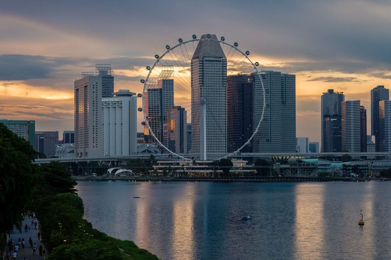 Stunning view of the Singapore skyline with the Ferris wheel at sunset, reflecting over Marina Bay.