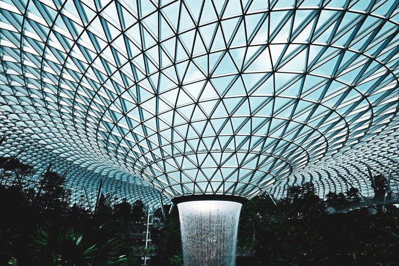 Dynamic interior view of Jewel Changi Airport's geometric ceiling with waterfall feature.
