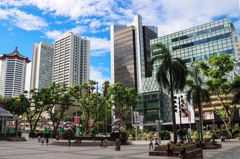 Explore the modern skyscrapers and bustling urban life of Singapore's cityscape under a bright blue sky.